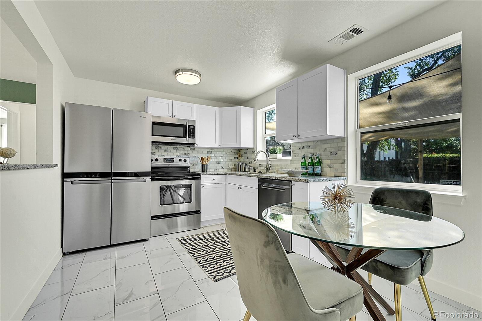 3011 Grape Street Denver, CO 80207 - Photo 3 of 42 a kitchen with stainless steel appliances granite countertop a refrigerator a stove a sink dishwasher and white cabinets with wooden floor