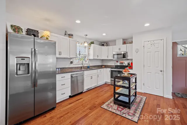 a kitchen with stainless steel appliances a refrigerator a stove a sink dishwasher and a refrigerator with wooden floor