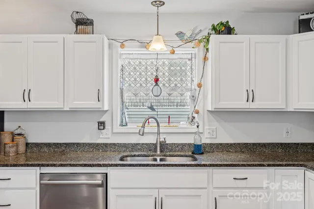 a kitchen with white cabinets and window