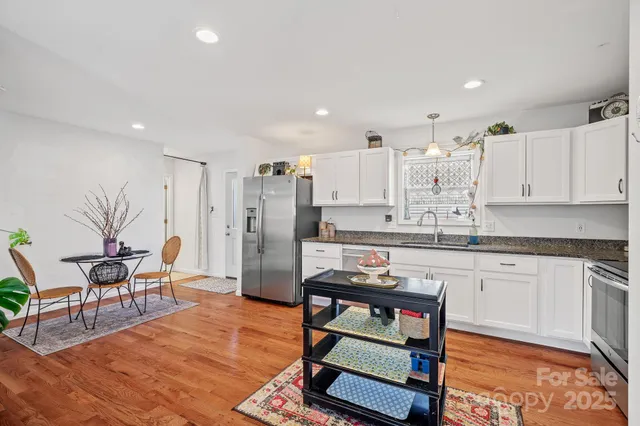 a living room with stainless steel appliances kitchen island granite countertop furniture and a wooden floor