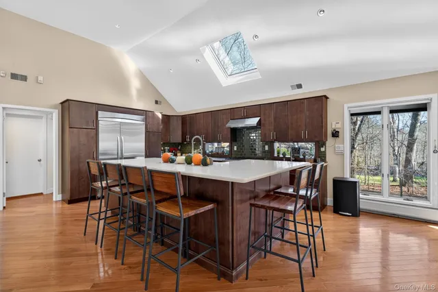 a kitchen with stainless steel appliances kitchen island granite countertop a table chairs in it and a wooden floors