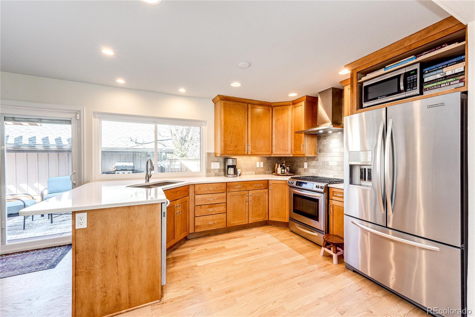 8712 Independence Way Arvada, CO 80005 - Photo 9 of 40 a kitchen with stainless steel appliances granite countertop a refrigerator a stove top oven a sink dishwasher and white cabinets with wooden floor