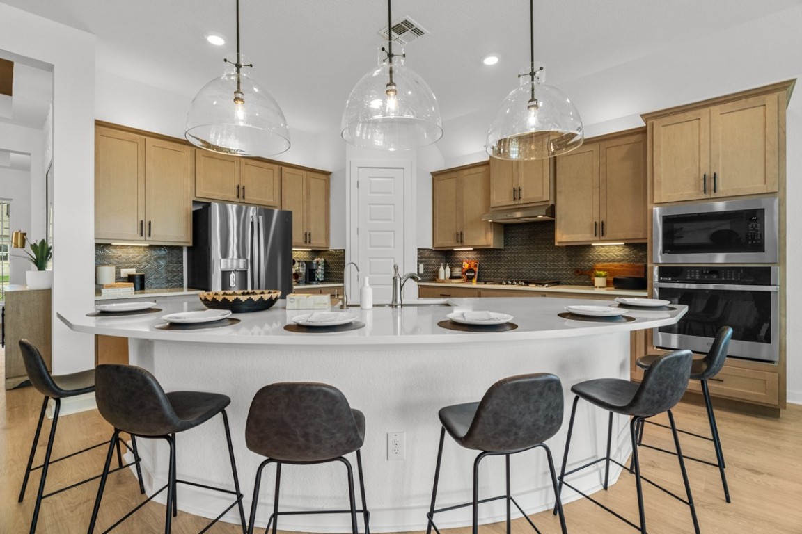1300 Snowdrop Drive Georgetown, TX 78628 - Photo 8 of 28 a kitchen with stainless steel appliances a stove a sink island and a refrigerator