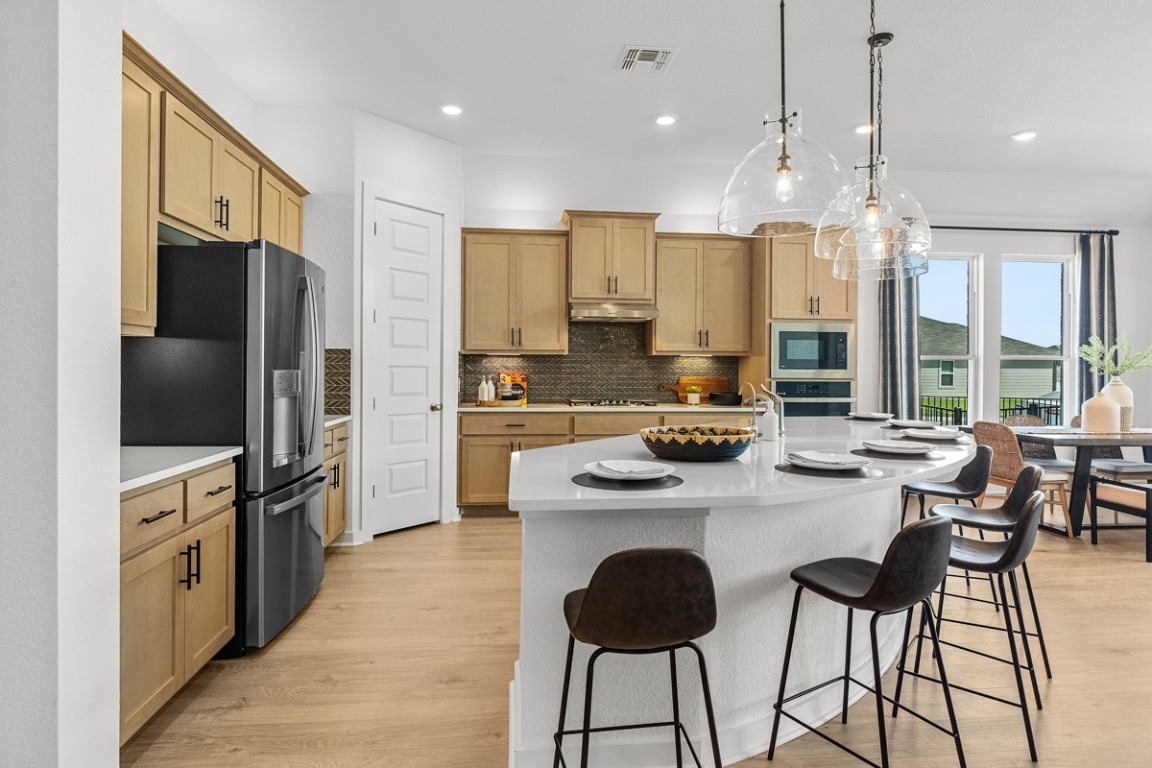 1300 Snowdrop Drive Georgetown, TX 78628 - Photo 9 of 28 a kitchen with stainless steel appliances kitchen island granite countertop a stove a refrigerator a oven a sink with a dining table and chairs