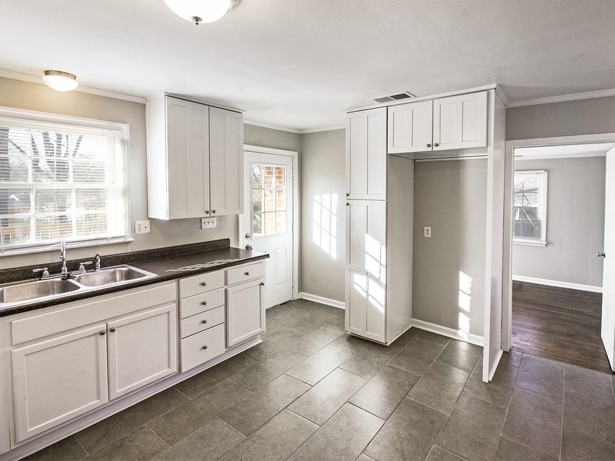 1019 Little John Road Memphis, TN 38111 - Photo 4 of 13 Kitchen with crown molding, white cabinetry, sink, and dark tile patterned floors