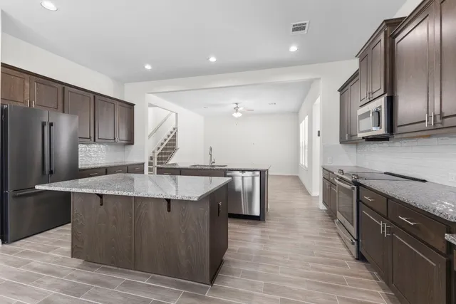 a kitchen with stainless steel appliances granite countertop a sink a stove and a refrigerator