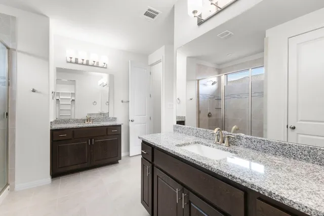 a bathroom with a granite countertop double vanity and a mirror