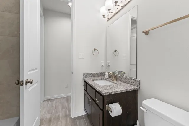 a bathroom with a granite countertop sink a toilet and shower