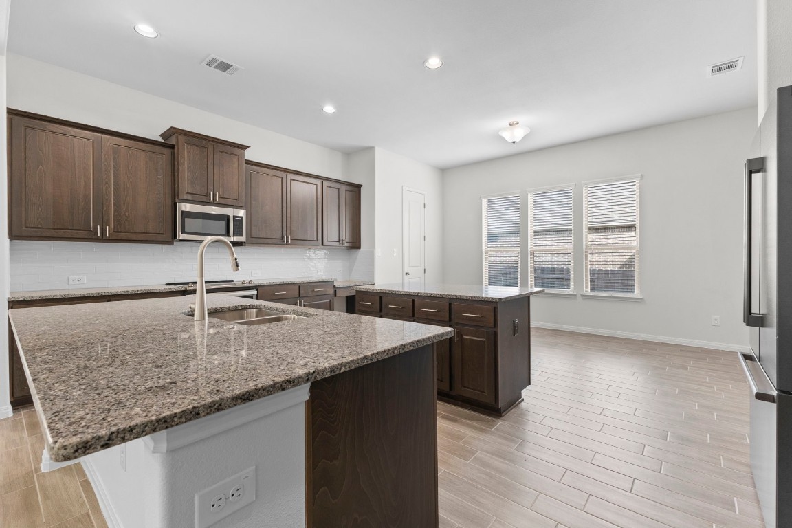 104 Scenic Hills Circle Georgetown, TX 78628 - Photo 8 of 30 a kitchen with stainless steel appliances granite countertop a sink a microwave counter space and wooden floor