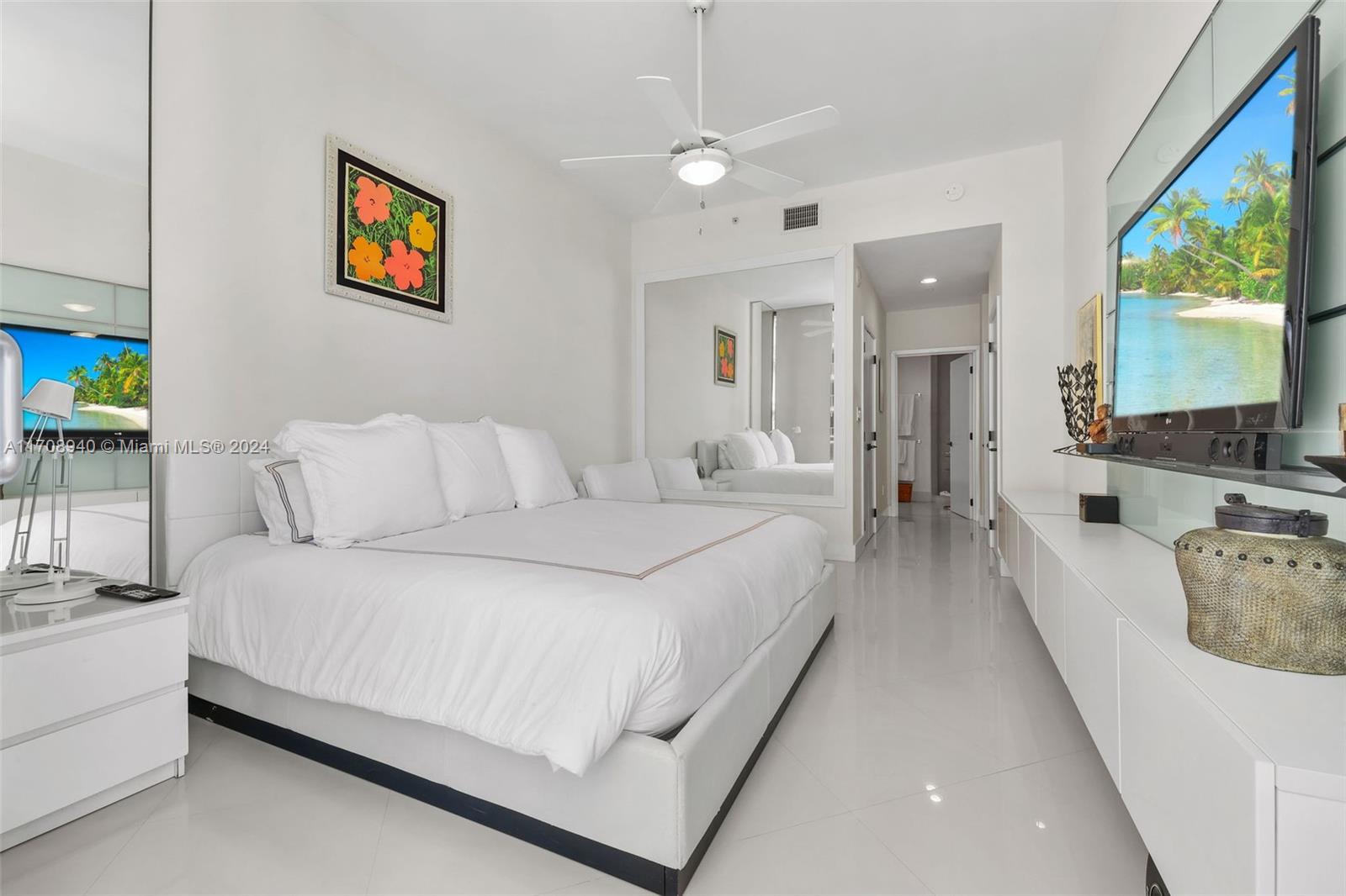 6799 Collins Avenue, Unit 207 Miami Beach, FL 33141 - Photo 13 of 35 a spacious bedroom with a bed a couch and a flat screen tv