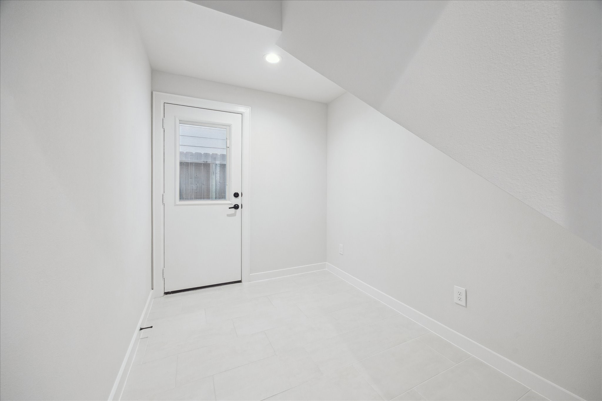 1603 Patterson Street, Unit E Houston, TX 77007 - Photo 6 of 32 The space has clean, white walls and a tiled floor, with a recessed light overhead. It's a compact area that could serve as a mudroom, a dog room, bike storage or simply a second office