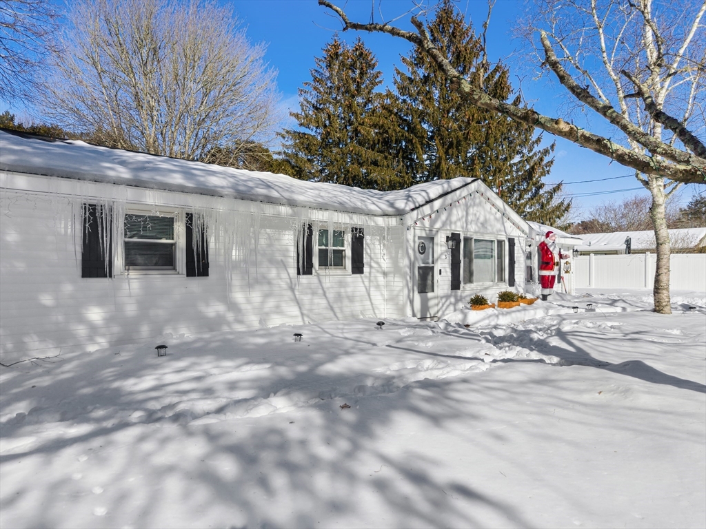 a view of a white house with a large tree and wooden fence