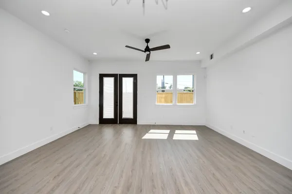an empty room with wooden floor chandelier and windows