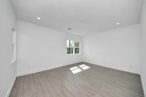 an empty room with wooden floor and windows