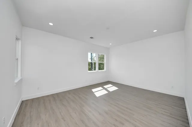 an empty room with wooden floor and windows