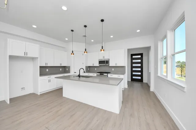 a kitchen with stainless steel appliances a stove top oven a sink a refrigerator and cabinets