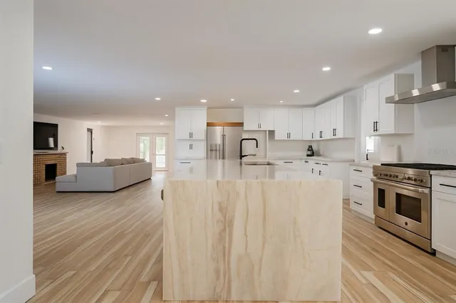 a kitchen with stainless steel appliances granite countertop a stove a sink and white cabinets