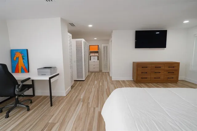 a spacious bedroom with a bed and a flat screen tv