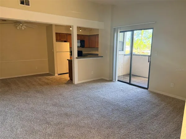 an empty room with windows and refrigerator