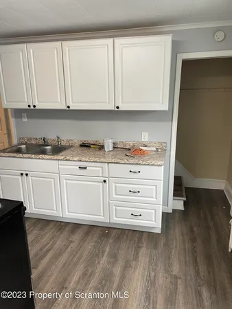 a kitchen with granite countertop white cabinets and sink