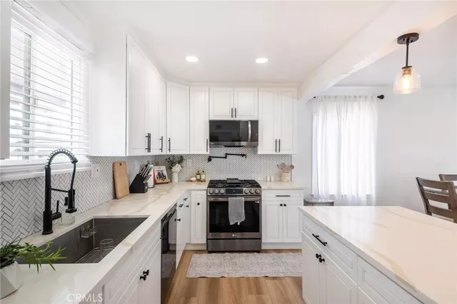 a large kitchen with a lot of white cabinets and stainless steel appliances