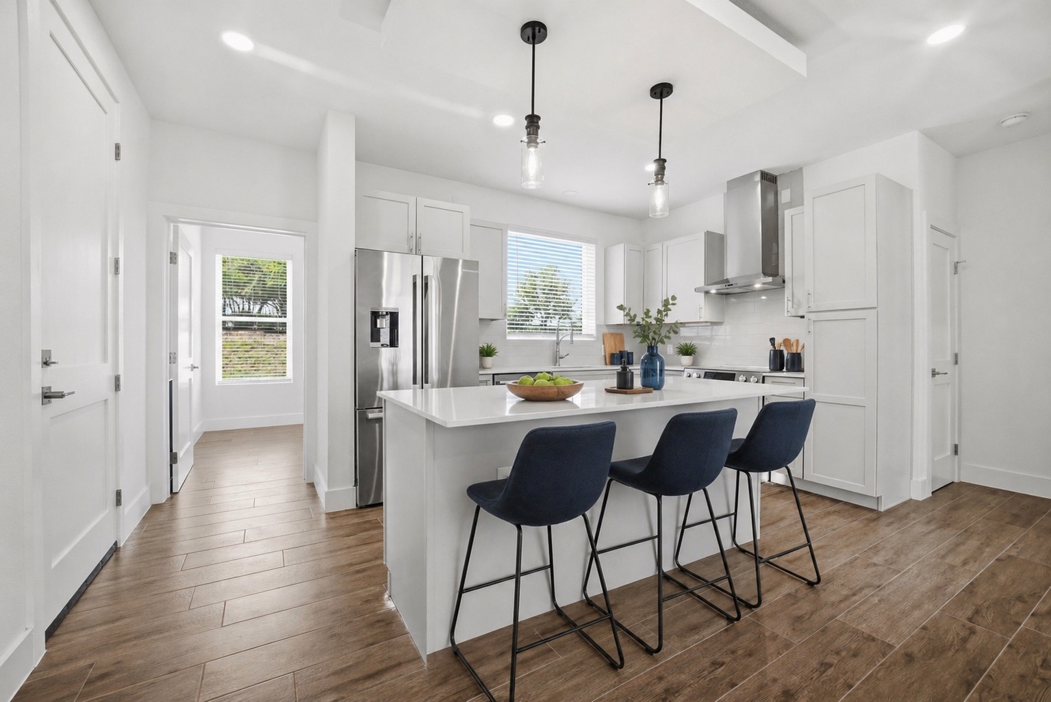 4300 Mansfield Dam Road, Unit 1021 Austin, TX 78734 - Photo 12 of 40 Contemporary kitchen featuring a large island with quartz countertops, stainless steel appliances, light gray cabinetry, and wood-look tile flooring; the door on the left opens to a private office.