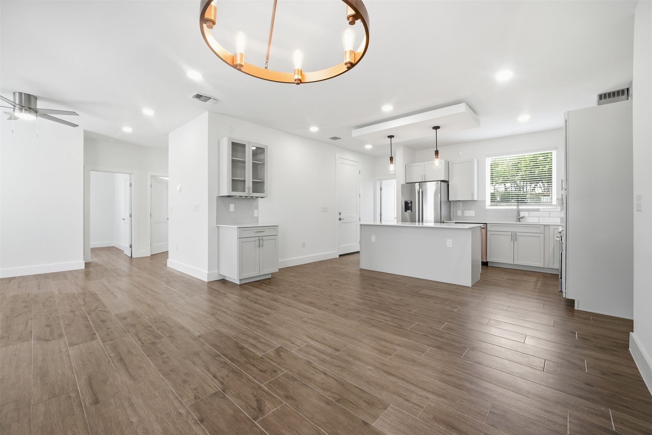 4300 Mansfield Dam Road, Unit 1021 Austin, TX 78734 - Photo 21 of 40 Open-concept living area featuring wood-finish flooring, a contemporary chandelier, recessed lighting, a modern kitchen island with pendant lights, and stainless steel appliances