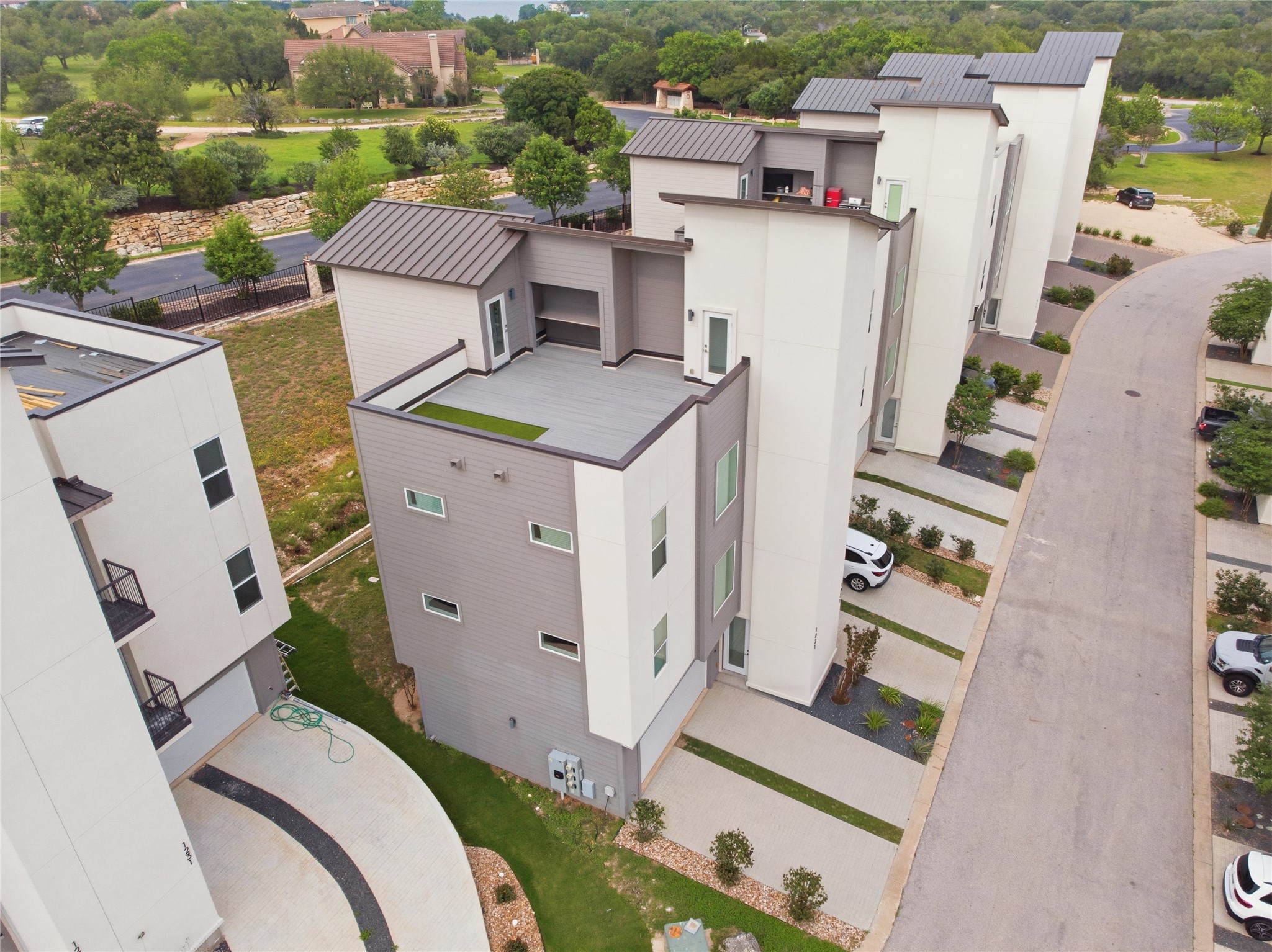 4300 Mansfield Dam Road, Unit 1021 Austin, TX 78734 - Photo 31 of 40 Modern townhomes featuring a rooftop deck with integrated turf, contemporary exterior finishes in white and gray.