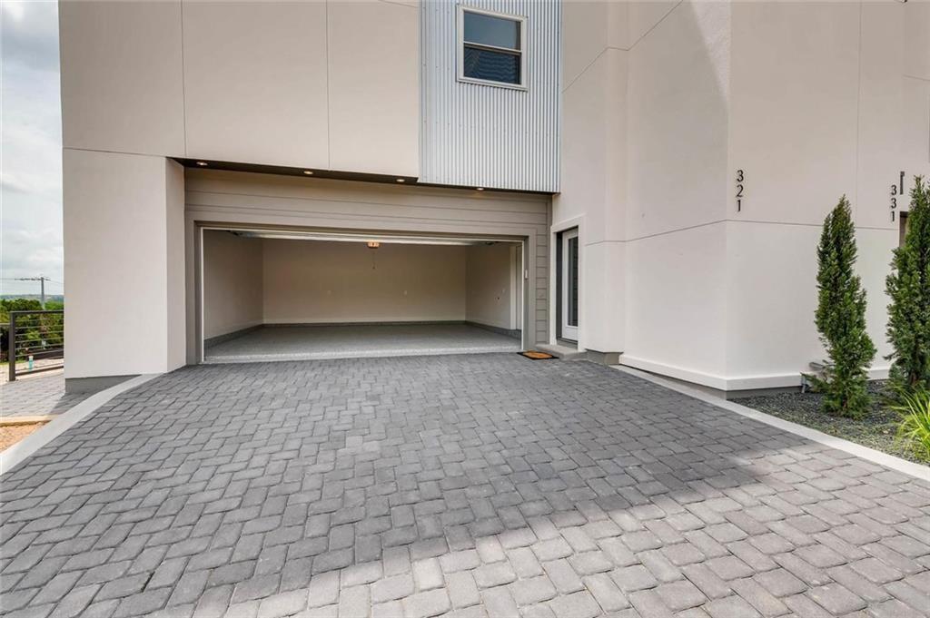 4300 Mansfield Dam Road, Unit 1021 Austin, TX 78734 - Photo 8 of 40 Leading to an extra-large two-car garage with a concrete floor, complemented by a paver driveway and equipped with an EV charger.