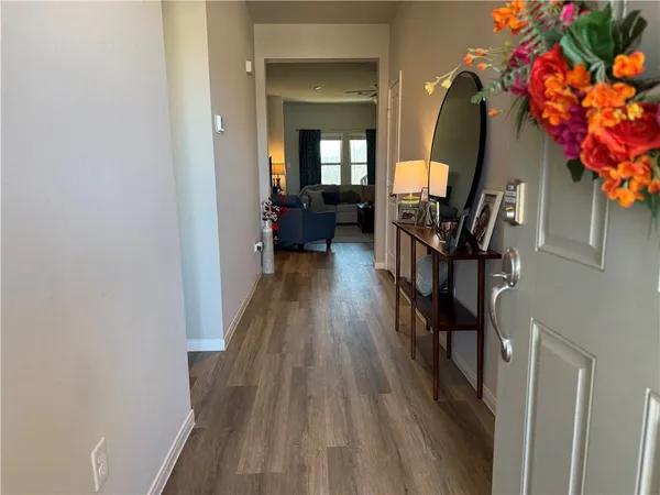 a view of a hallway with wooden floor and a potted plant