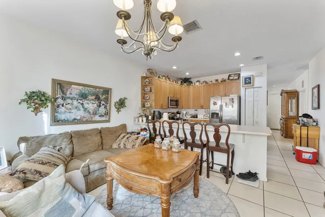 a living room with furniture a chandelier and kitchen view