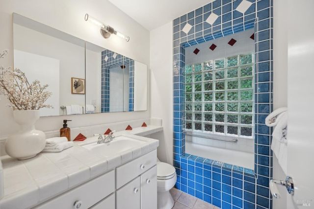 a bathroom with a granite countertop sink a toilet and shower