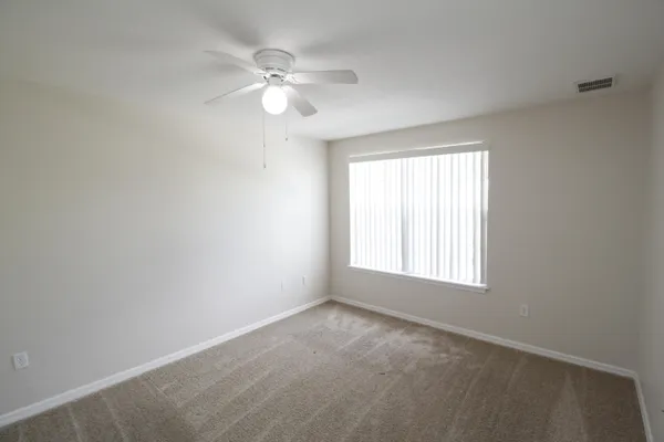 an empty room with windows and fan