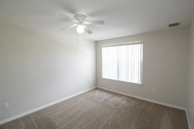an empty room with windows and fan