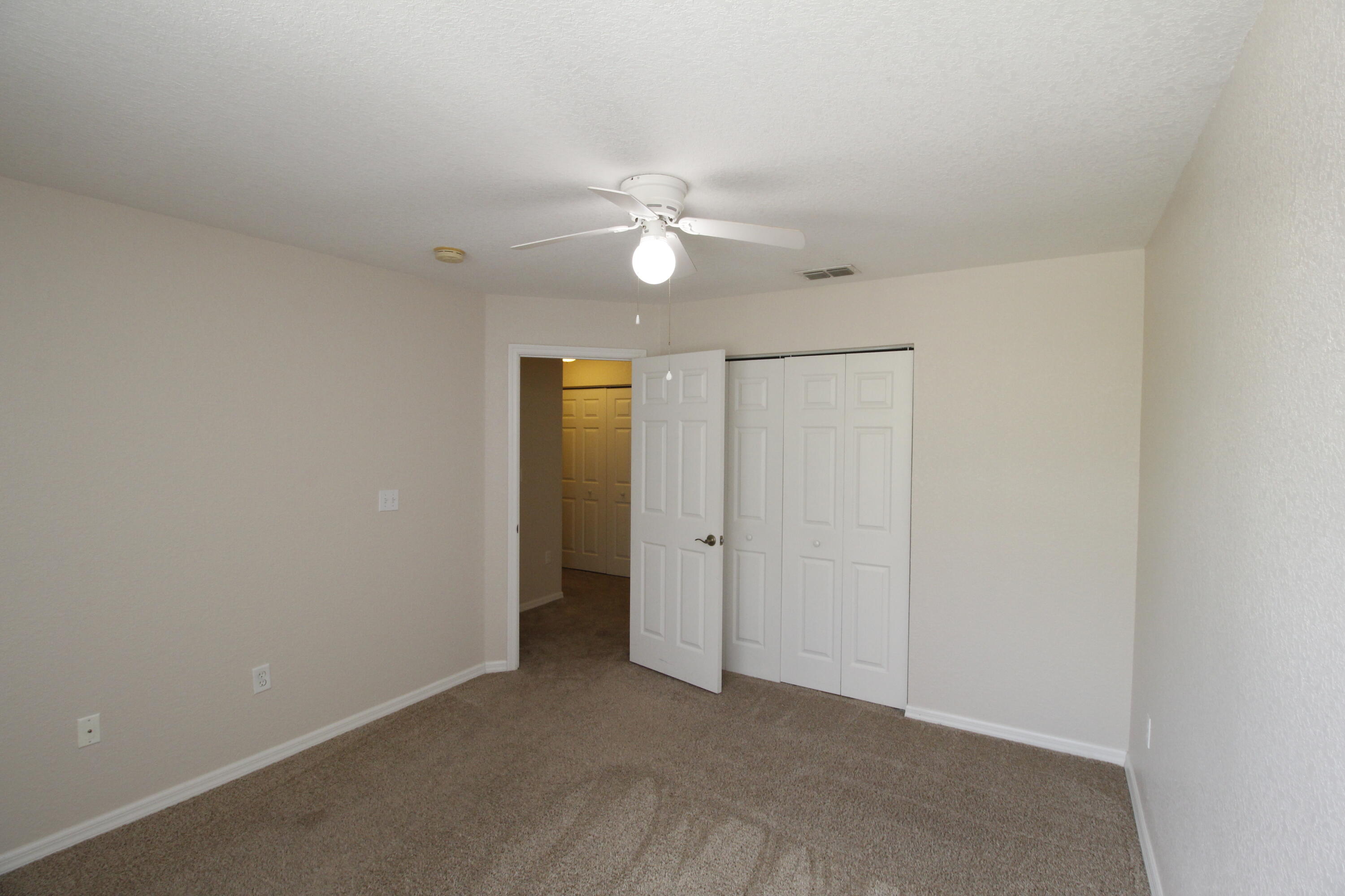 105 Turpial Way, Unit 103 Melbourne, FL 32901 - Photo 13 of 16 an empty room with closet and a ceiling fan