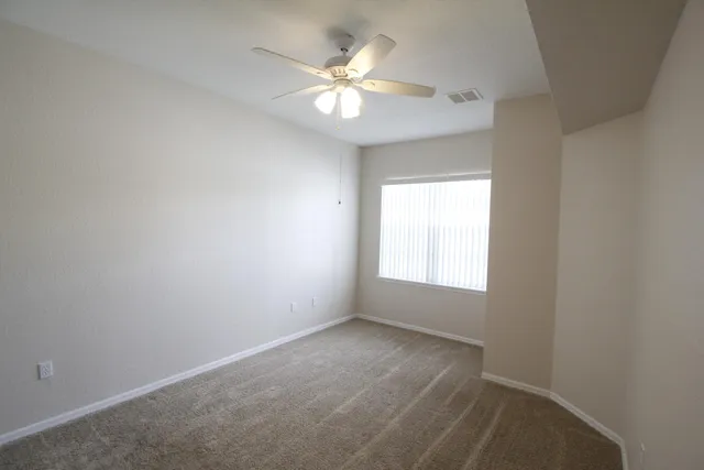 an empty room with windows and chandelier fan