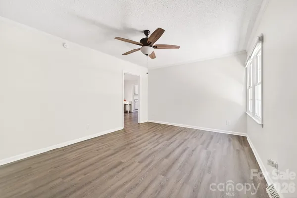 an empty room with wooden floor a ceiling fan and windows