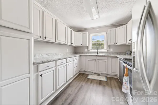 a kitchen with granite countertop white cabinets and white appliances