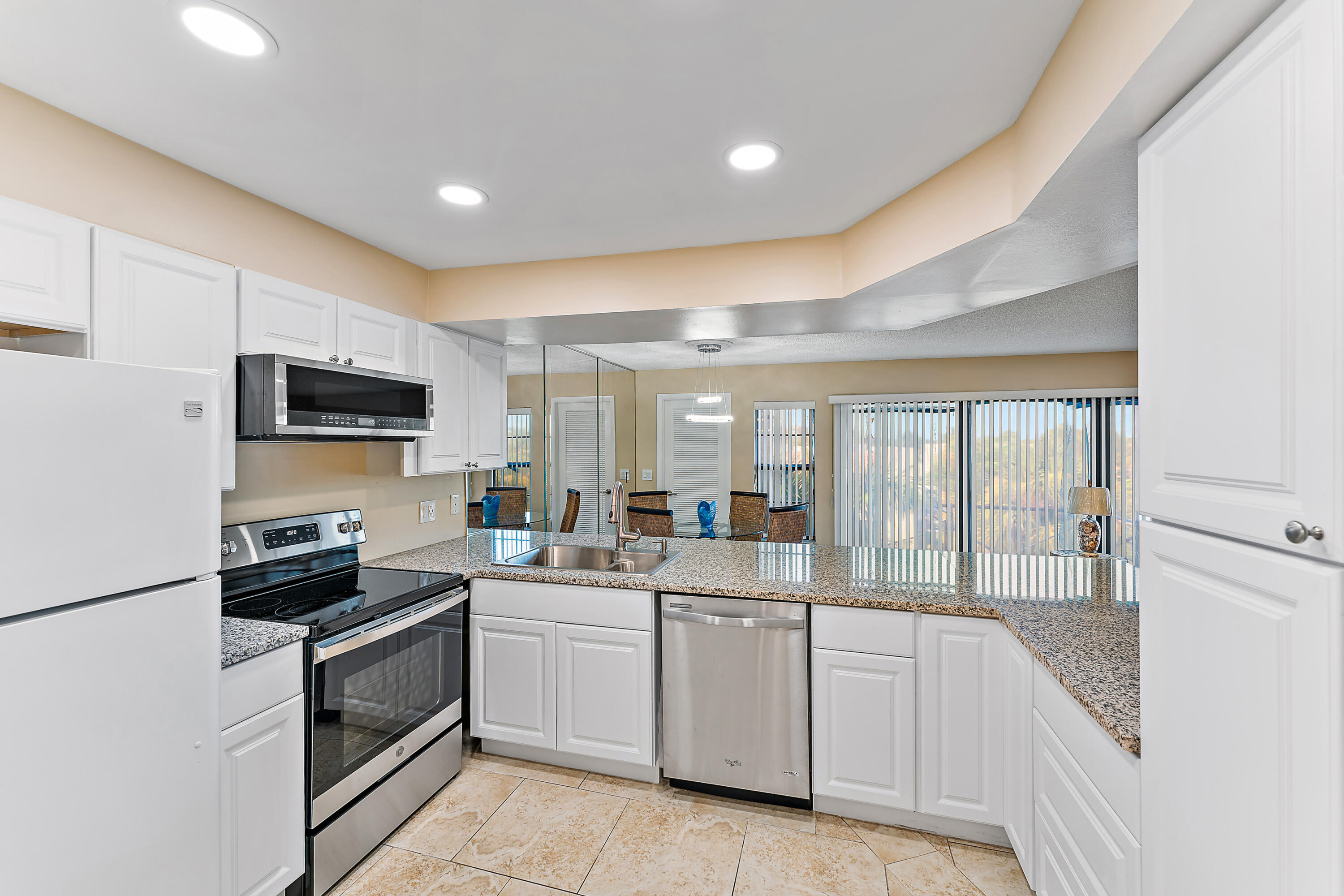 1605 Highway 1, Unit V6306 Jupiter, FL 33477 - Photo 17 of 34 a kitchen with a sink dishwasher stove and white cabinets with wooden floor