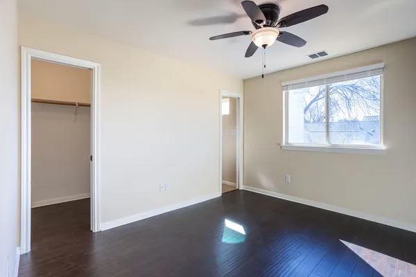 a view of empty room with wooden floor and fan