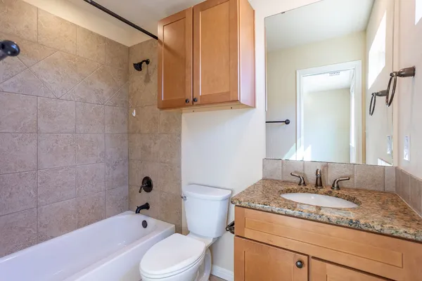 a bathroom with a granite countertop sink toilet and shower