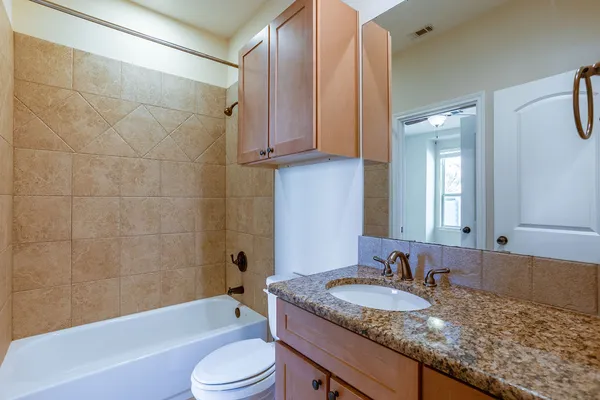 a bathroom with a granite countertop sink toilet and shower