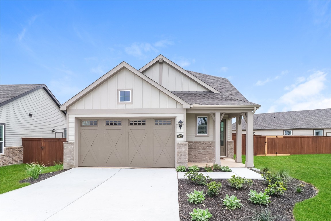 Craftsman-style house with board and batten siding, concrete driveway, roof with shingles, a porch, and brick siding