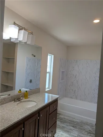 a bathroom with a granite countertop sink a mirror and bathtub
