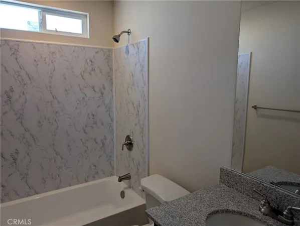 a bathroom with a granite countertop sink and a bathtub