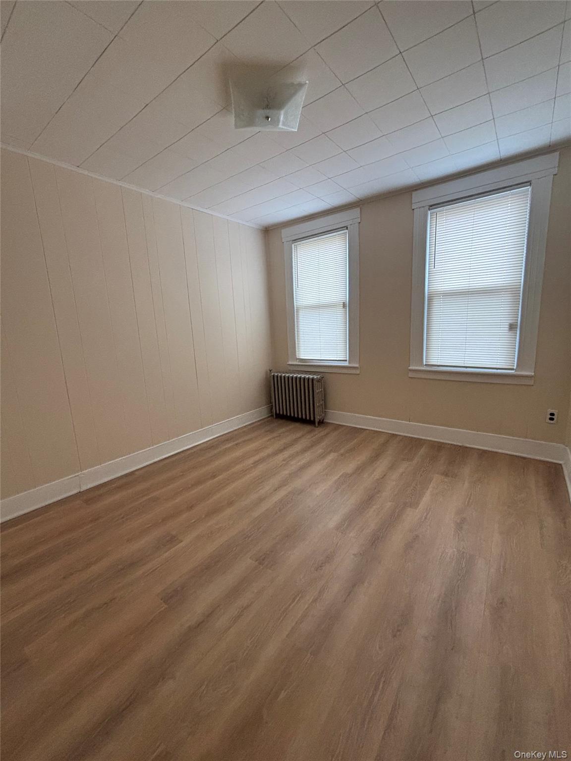 55-12 Van Cleef Street Queens, NY 11368 - Photo 6 of 8 an empty room with wooden floor and windows
