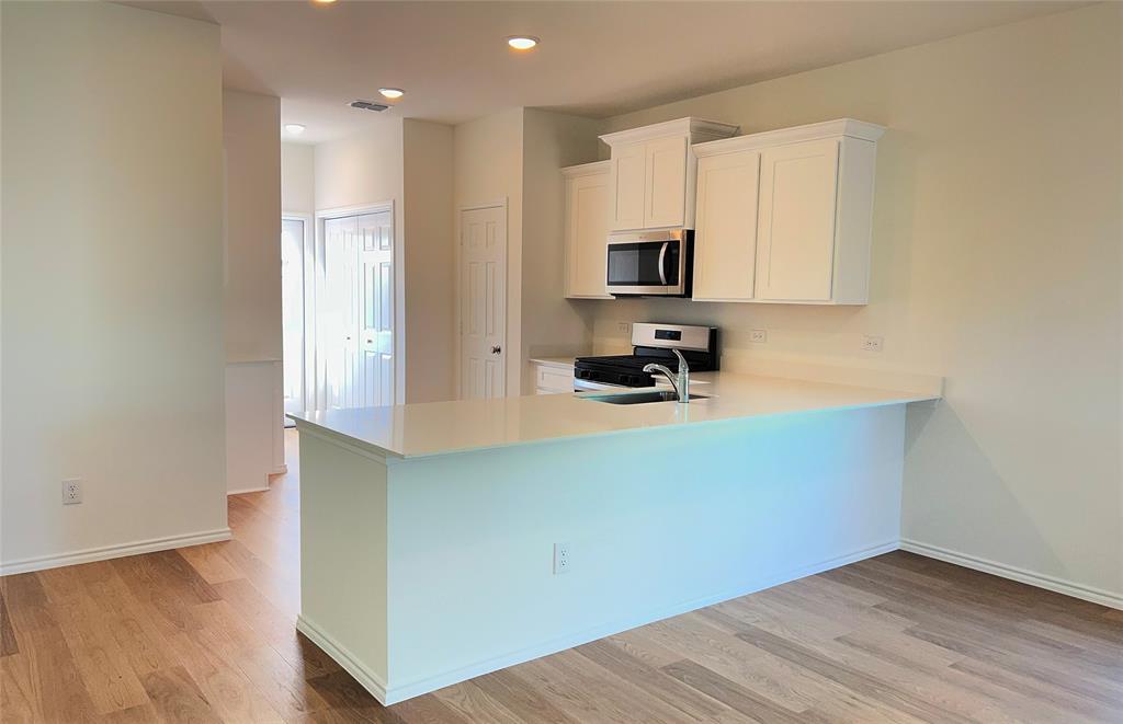 2534 Midfield Way Princeton, TX 75407 - Photo 2 of 14 a kitchen with stainless steel appliances a stove a microwave a sink and cabinets