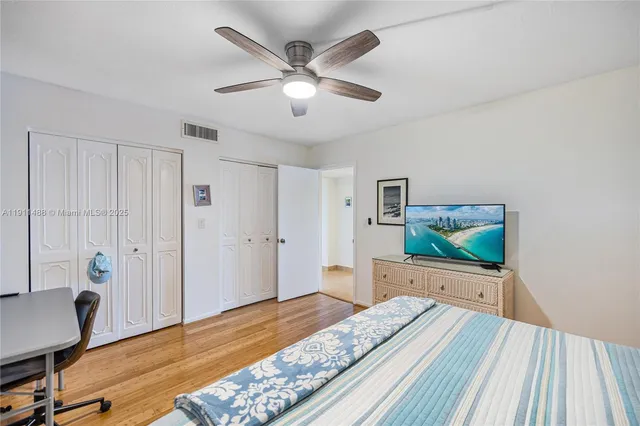 a bedroom with a bed and a dresser with wooden floor