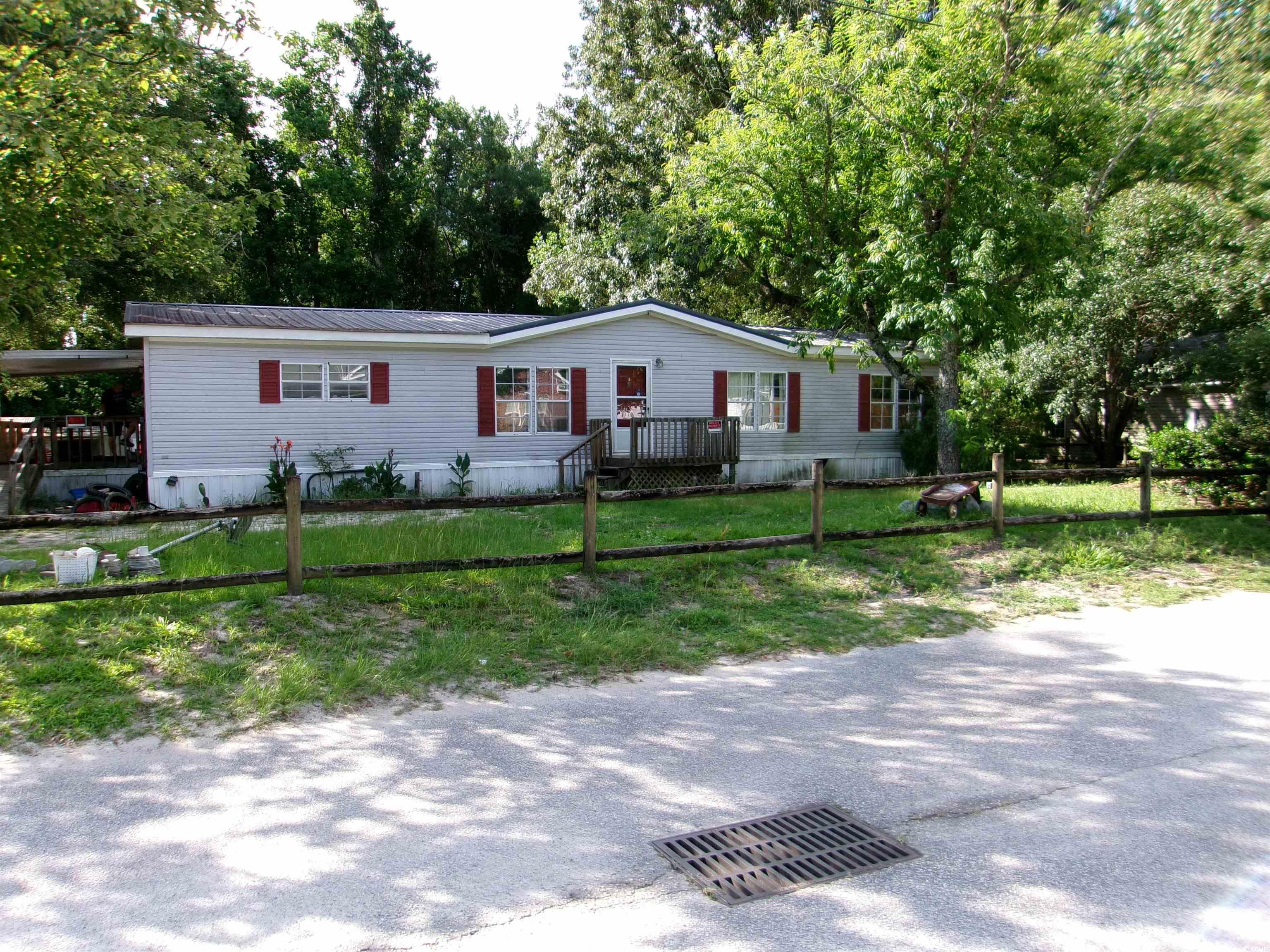 4261 Blake Road Myrtle Beach, SC 29588 - Photo 1 of 11 Manufactured / mobile home featuring a front lawn, a metal roof, and view of wooded area