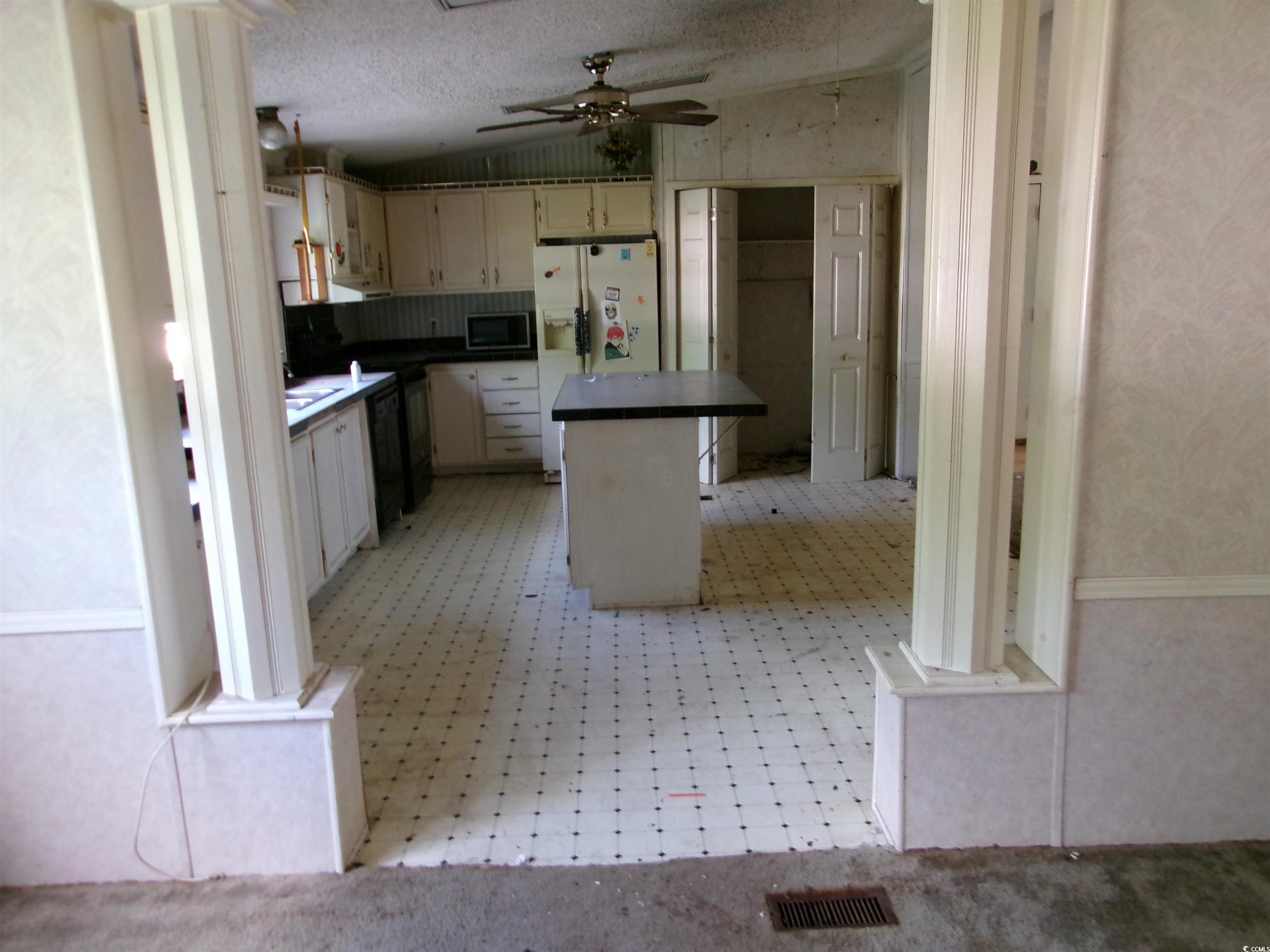 4261 Blake Road Myrtle Beach, SC 29588 - Photo 4 of 11 Kitchen with stainless steel microwave, white fridge with ice dispenser, a center island, dark countertops, and a ceiling fan